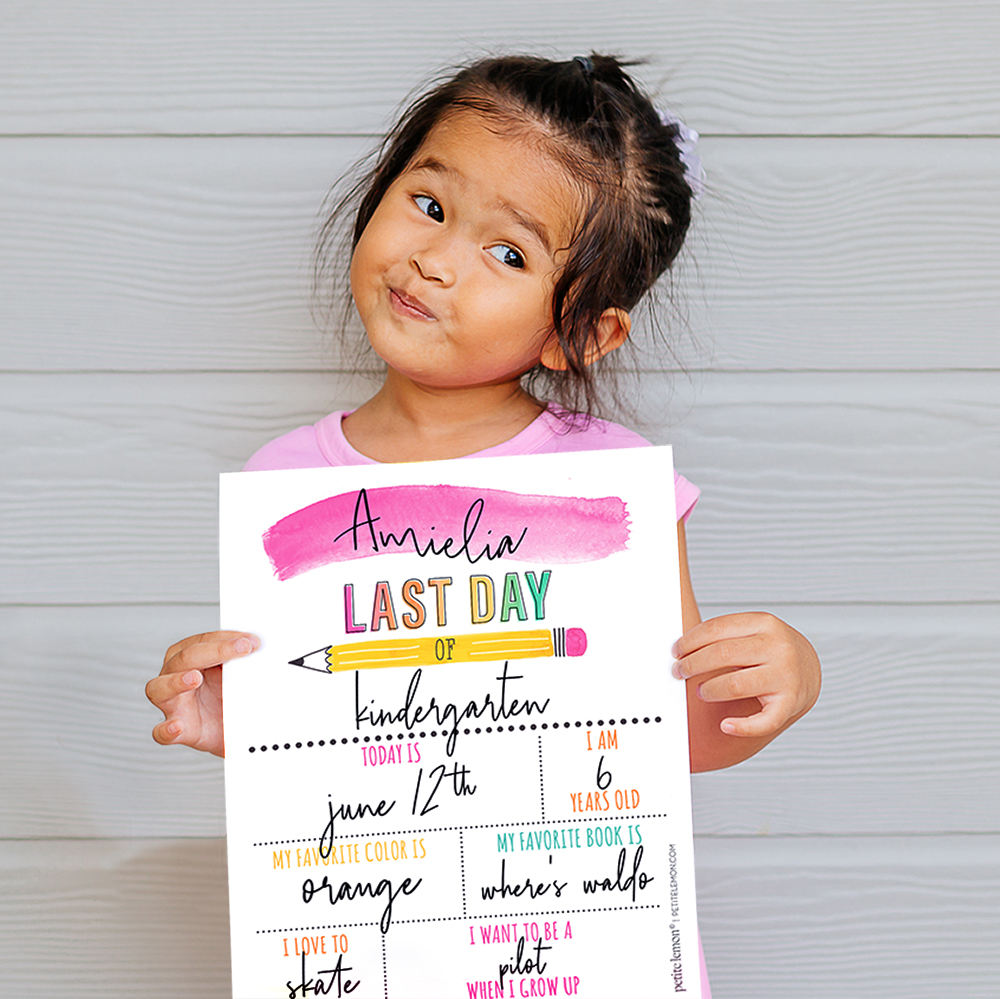 girl in pink dress holding last day of school sign